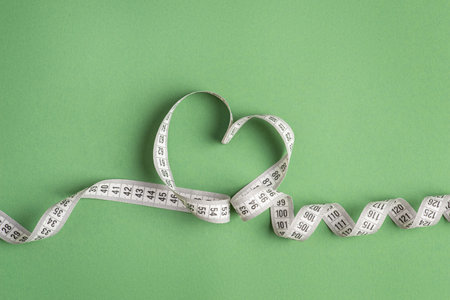 White measuring tape on a green backgroundの写真素材