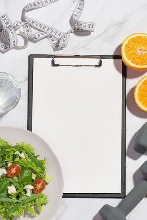 gray background with tablet, lettuce, orange, dumbbells and measuring tapeの写真素材