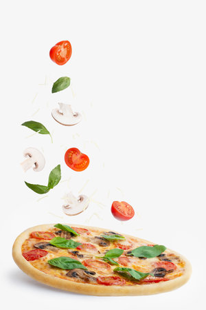 Pizza with mushrooms, tomatoes, cheese and basil on a white background. Falling ingredients. Levitationの写真素材