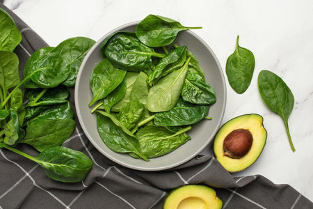 Gray culinary background with ingredients for green salad. Spinach with avocado and grapes.