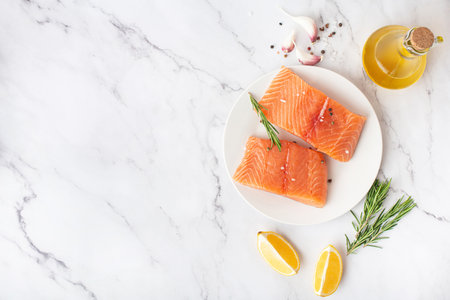 Fresh raw trout fillet with spices and lemon on a white table. food preparation, culinary backgroundの写真素材