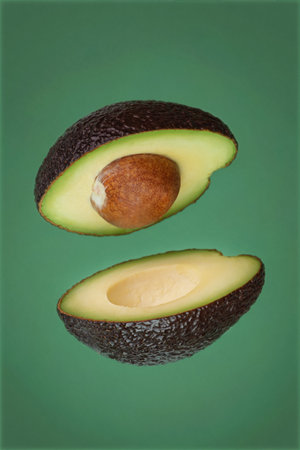 flying cut avocado on green background
