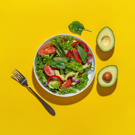 Vegetable salad with avocado in a white plate on a yellow background. Cooking. Diet.の写真素材