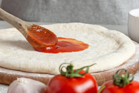 The process of making margarita pizza. Male hands, top view. Tomato paste with cheese.の写真素材