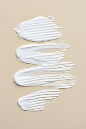 Smears of white cream on a beige background, cream texture