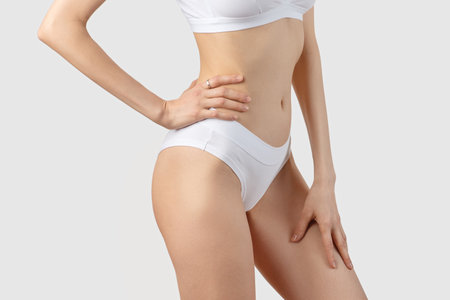 young slender woman in white lingerie on a gray backgroundの写真素材