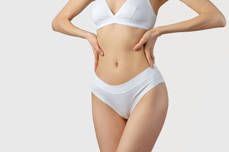 young slender woman in white lingerie on a gray backgroundの写真素材