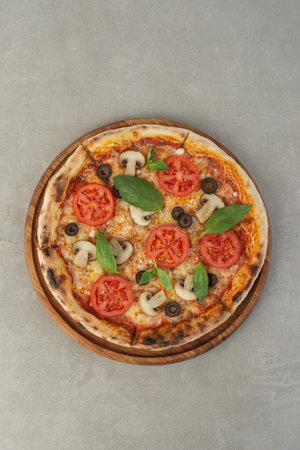 Pizza margherita with tomatoes and mushrooms on a gray background, top viewの写真素材