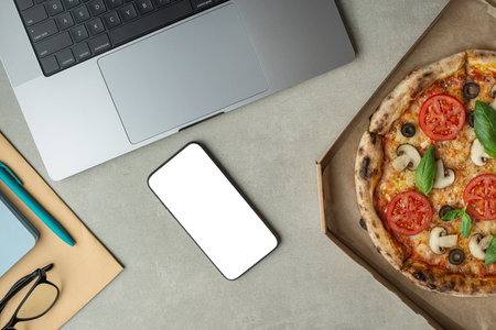 A man works and eats pizza, top view, hands on the desktop. Pizza delivery.の写真素材