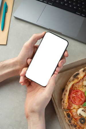 A man works and eats pizza, top view, hands on the desktop. Pizza delivery.の写真素材