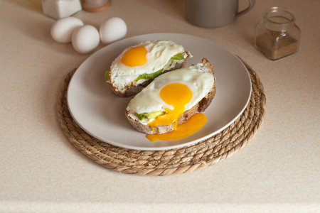 Fried eggs on toast bread with butter and lettuce on a plateの写真素材