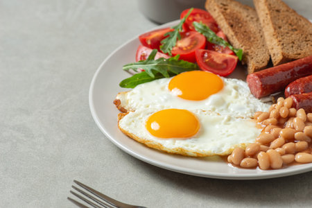 Fried eggs with sausages and beans in a plate on a gray background. English breakfastの写真素材