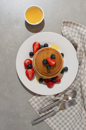 pancakes with berries and honey on a gray tableの写真素材