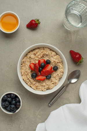 Oatmeal with berries and honey on a gray tableの写真素材