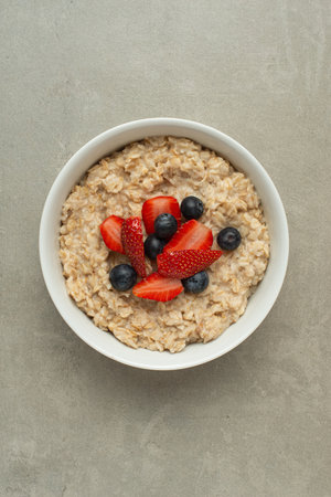 Oatmeal with berries and honey on a gray table