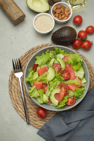Vegetable salad with tomatoes, avocado and cucumber on a gray backgroundの写真素材