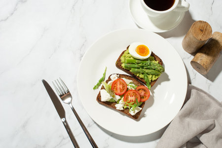 Toasts with egg, avocado and other vegetables on a gray background in a plate. healthy breakfastの写真素材