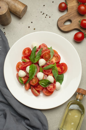 Salad with tomatoes, mozzarella and basil on a gray backgroundの写真素材