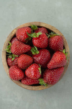 strawberries in a wooden plate on a gray backgroundの写真素材