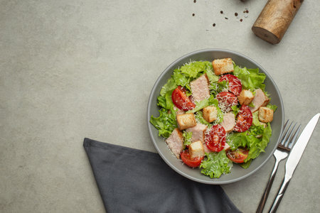 Vegetable salad with chicken and cheese on a gray table. Caesar salad in a gray plate.の写真素材