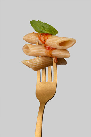 pasta with sauce and basil on a golden fork