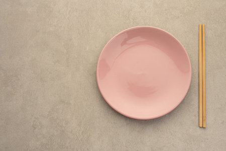 Pink Ceramic Bowl with Wooden Chopsticks on Neutral Background