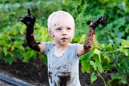 child with blue eyes playing in the mud in the summer on the streetの写真素材
