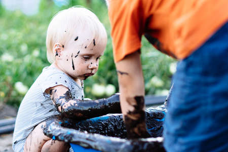 child with blue eyes playing in the mud in the summer on the streetの写真素材