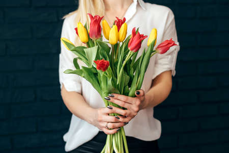 beautiful yellow and pink tulips girl holding hands on black backgroundの写真素材