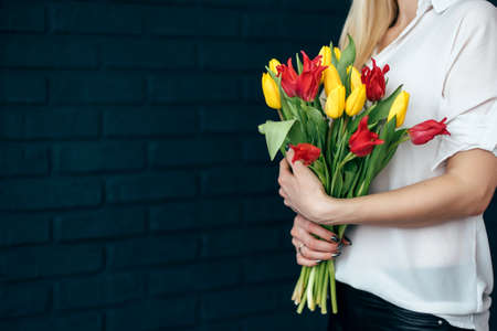 Beautiful yellow and pink tulips girl holding hands on black backgroundの写真素材