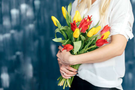 beautiful yellow and pink tulips girl holding hands on blue backgroundの写真素材