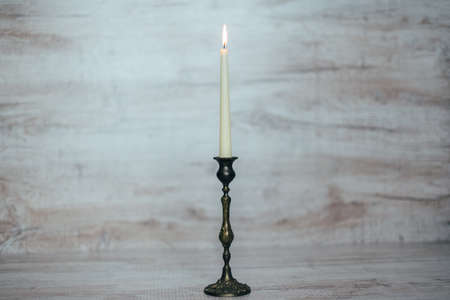 antique candlestick with a burning candle on a wooden backgroundの写真素材