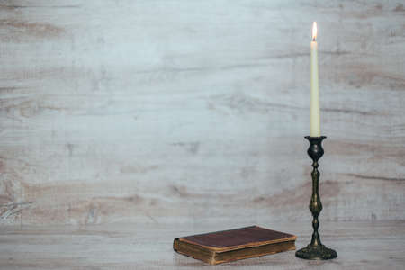 antique candlestick with a burning candle on a wooden backgroundの写真素材