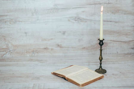 antique candlestick with a burning candle on a wooden backgroundの写真素材