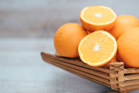 cut fresh juicy orange on a wooden vase on a wooden backgroundの写真素材