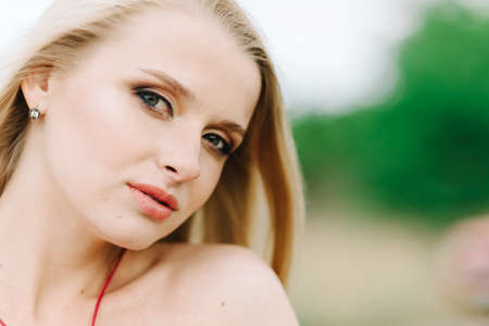 young girl with white hair on nature on a green background in a red dress without photoshopの写真素材