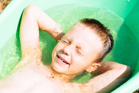 a dirty child with blue eyes is played outdoors in nature in the village in the summerの写真素材