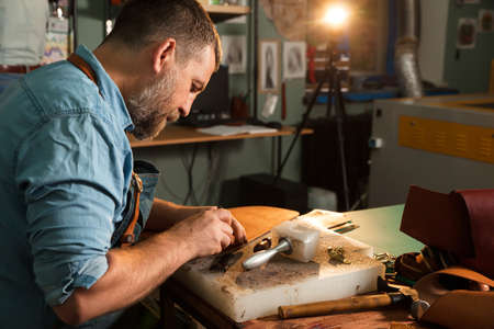 Man working with leather using crafting tools.の写真素材