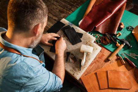 Man working with leather using crafting tools.