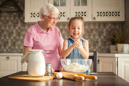 Cute little girl and her grandmother cooking on kitchen.の写真素材
