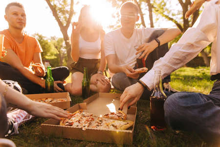 Five young cheerful friends eating pizza outdoorsの写真素材