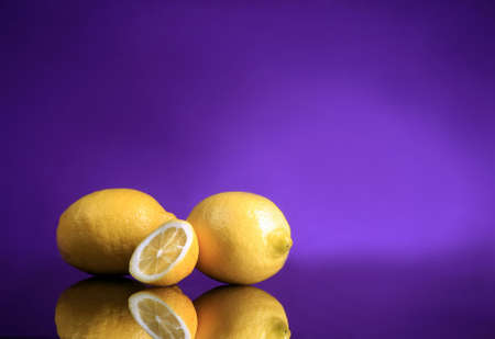 two lemons standing with a purple background