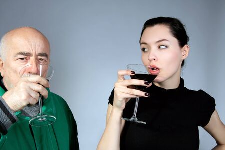 senior man and girl are tasting red wineの写真素材