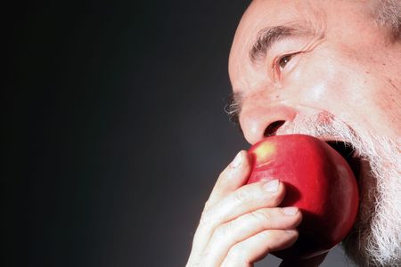 a senior gentleman is eating red appleの写真素材