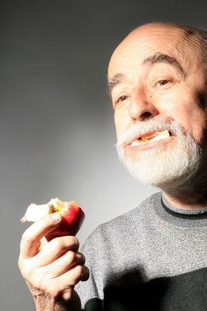 a senior gentleman is eating red appleの写真素材