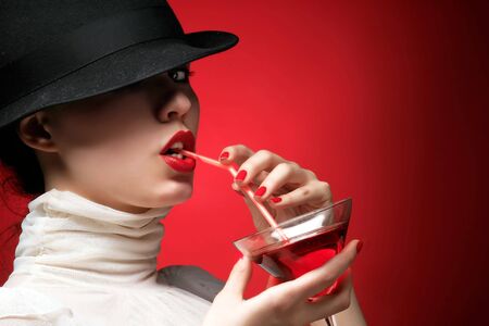 a glamor lady with hat is drinking cocktailの写真素材