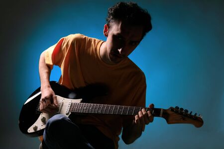 a man is playing an electric guitar on blueの写真素材
