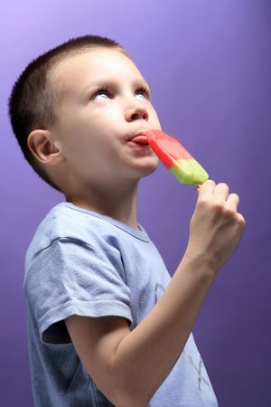photo of a boy eating color ice creamの写真素材
