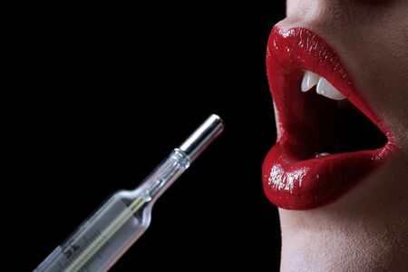 a red woman lips with thermometer on the black backgroundの写真素材