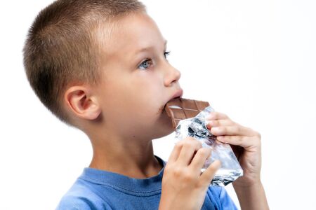 kid eating chocolate , while smearing his face with choclateの写真素材